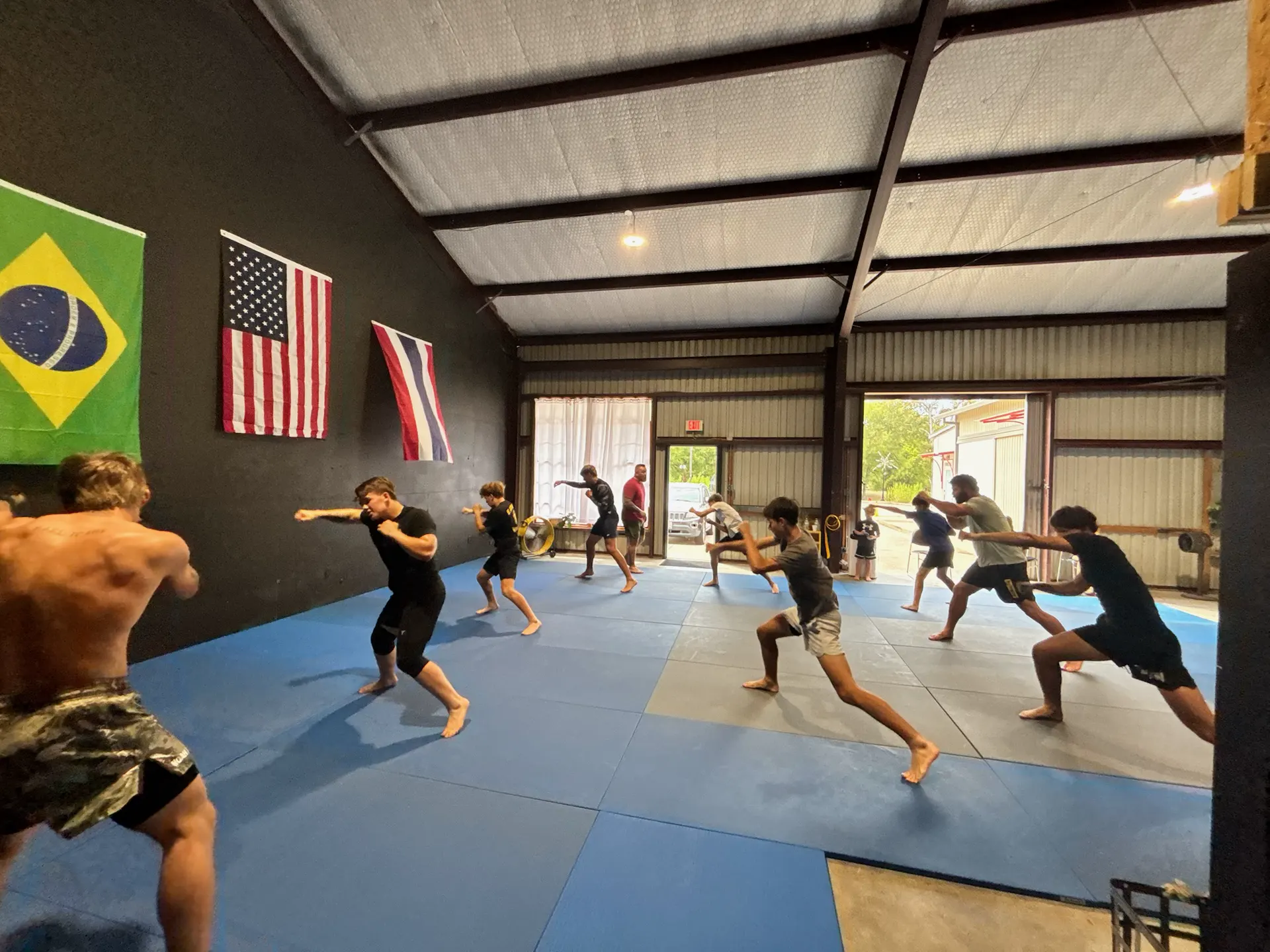 Teens and adults shadowboxing in rows across the mats during an Apex MMA class