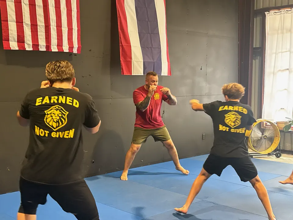 Founder James Larremore squaring up with two young students in Earned Not Given shirts