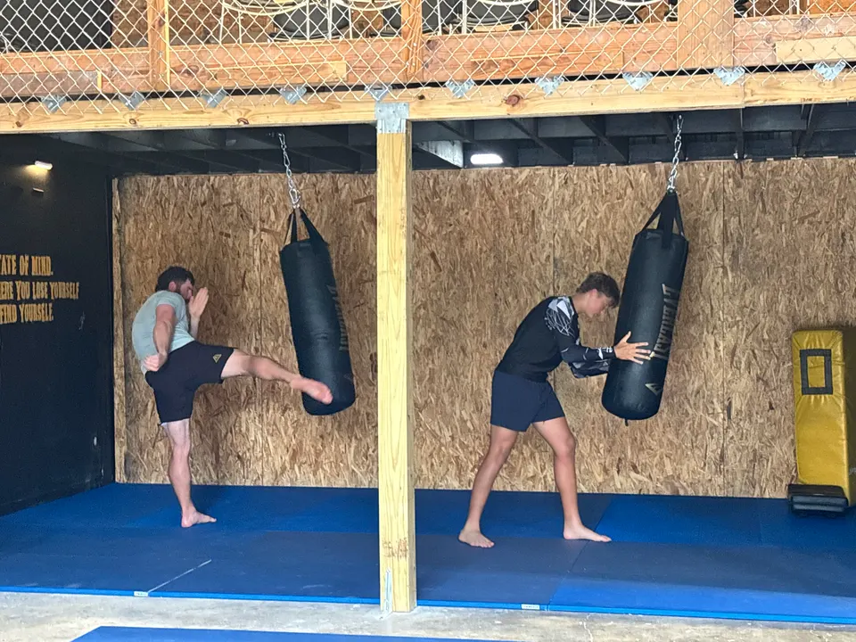 Two athletes kicking and clinching heavy bags